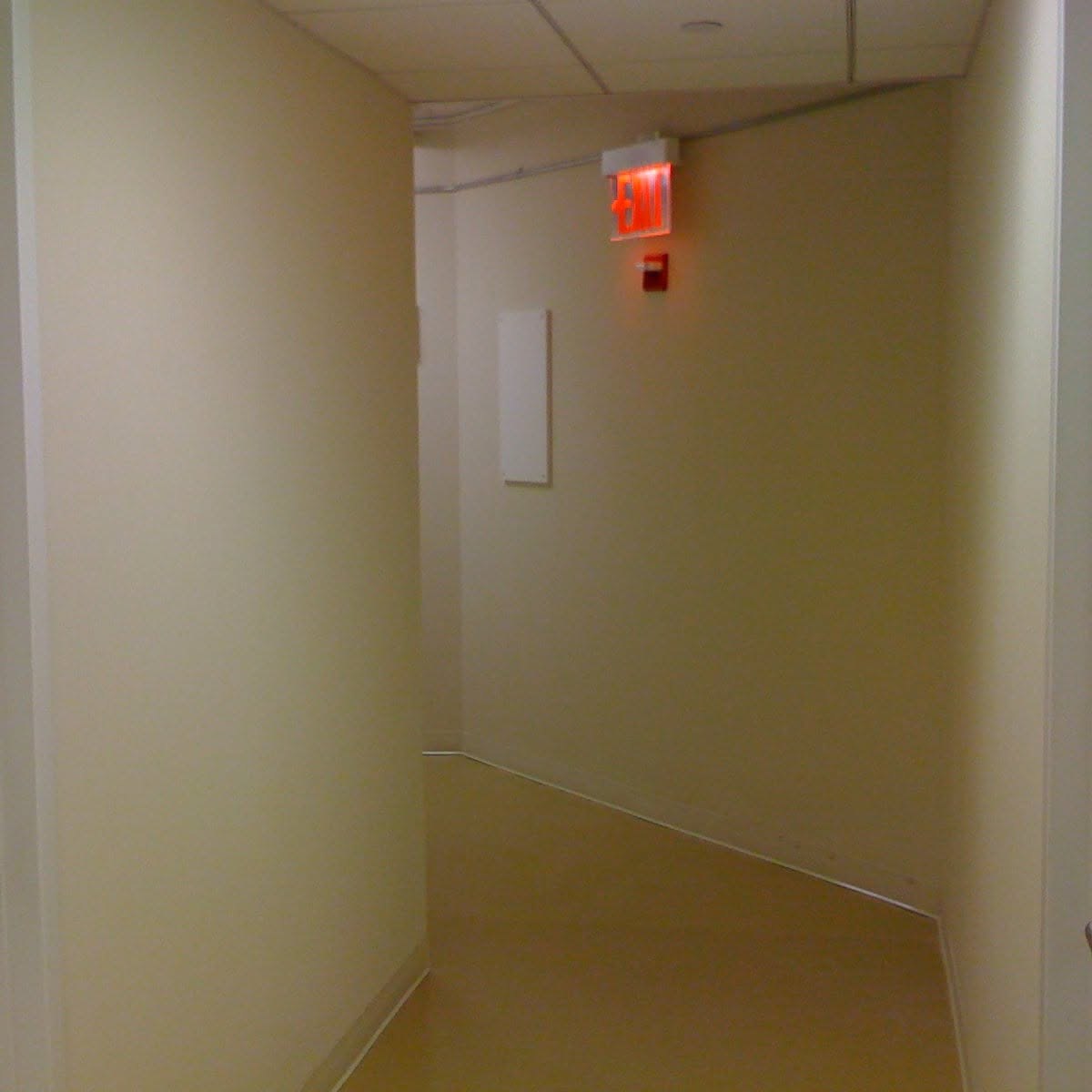 Finished commercial hallway with wiring, fixtures, and emergency lighting
